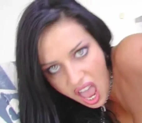 Dark-haired woman leaning toward the camera with a tense direct gaze.